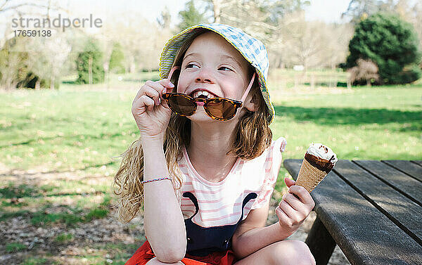 Mädchen isst im Sommer glücklich Eis im Park