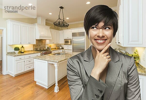 Hübsche gemischtrassige Frau blickt über die Schulter zurück in eine individuell gestaltete Küche