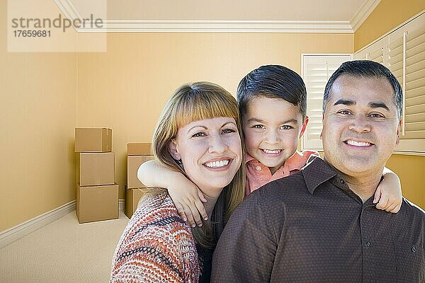 Glückliche junge gemischtrassige Familie in einem Raum mit Umzugskartons