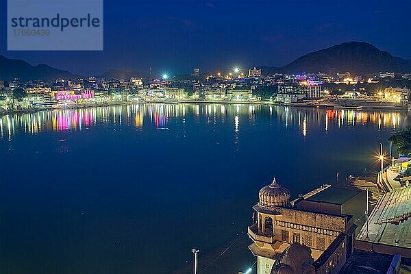 Night view of famous indian hinduism pilgrimage town sacred holy hindu religious city Pushkar with Brahma temple  aarti ceremony  lake and ghats illuminated. Rajasthan  India. Horizontal pan