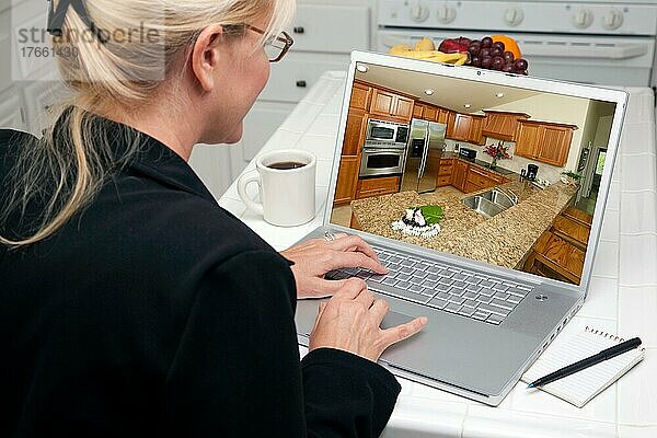 Frau in der Küche  die einen Laptop benutzt  um Heimwerkerideen zu recherchieren. Der Bildschirm kann leicht für eigene Nachrichten oder Bilder verwendet werden. Das Bild auf dem Bildschirm ist auch mein Copyright