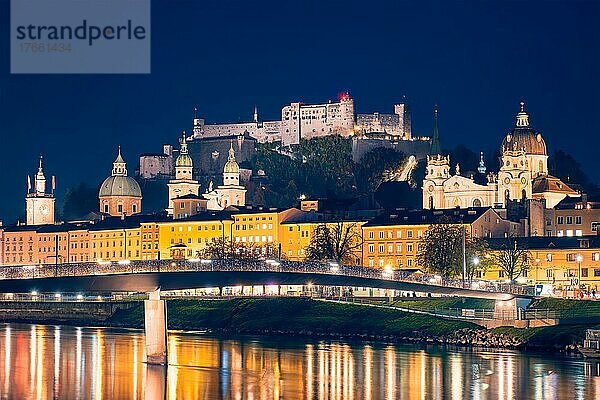 Salzburg city evening view. Cathedral  Old Town Altstadt  Hohensalzburg castle illuminated at night. Salzach River waterfront with promenade. Salzburg  Austria