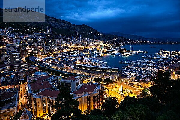 Aerial view of Monaco Monte Carlo harbour and illuminated city skyline in the evening blue hour twilight. Monaco Port night view with luxurious yachts