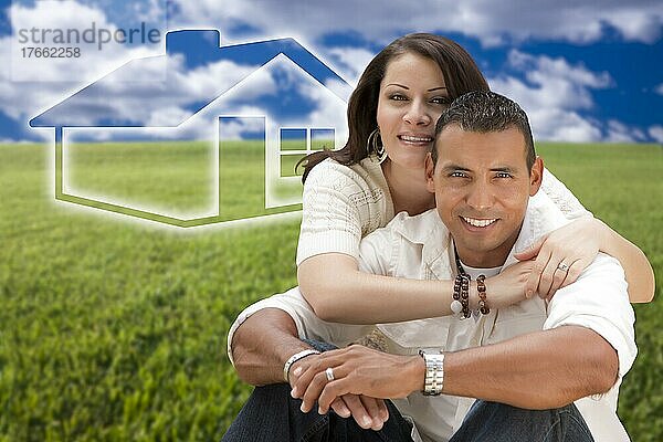 Happy hispanic couple sitting in graß field with ghosted house figure behind them