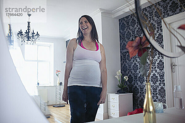 Glückliche schwangere Frau in Athleisure-Kleidung zu Hause