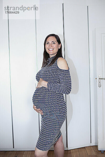 Porträt lächelnde schwangere Frau im Kleid