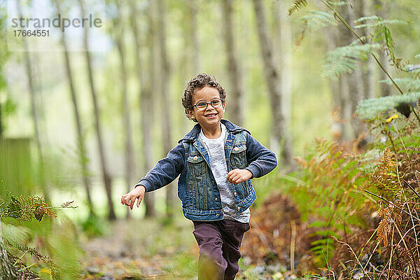 Porträt glücklicher Junge läuft im Wald