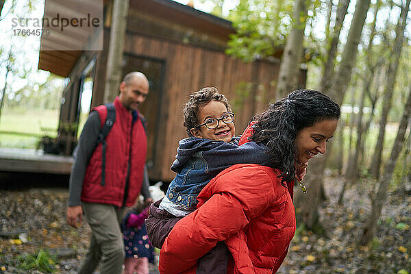 Porträt einer Mutter  die ihren Sohn auf einer Wanderung im Wald huckepack nimmt