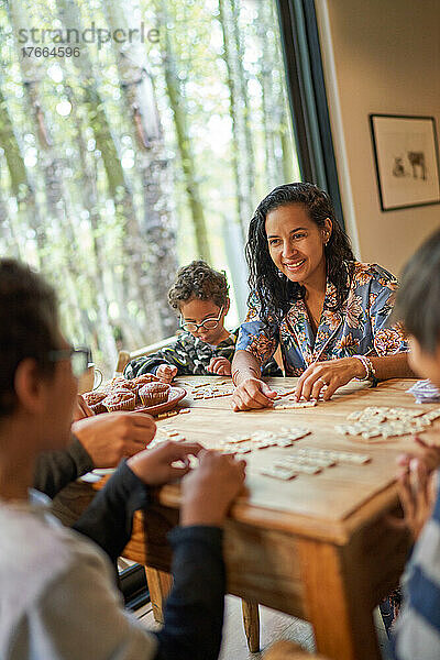 Glückliche Familie spielt Scrabble am Esstisch