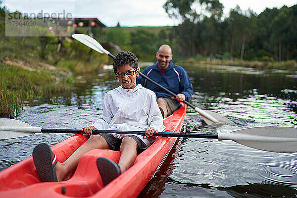 Portrait glücklicher Vater und Sohn beim Kajakfahren auf dem Fluss