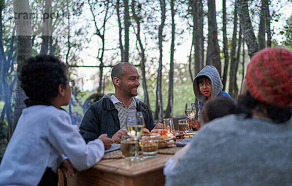 Glückliche Familie beim Essen am Tisch im Wald