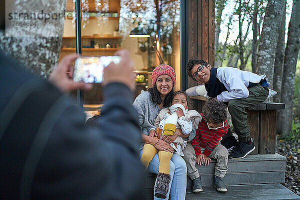 Glückliche Familie posiert für ein Foto vor einer Hütte im Wald