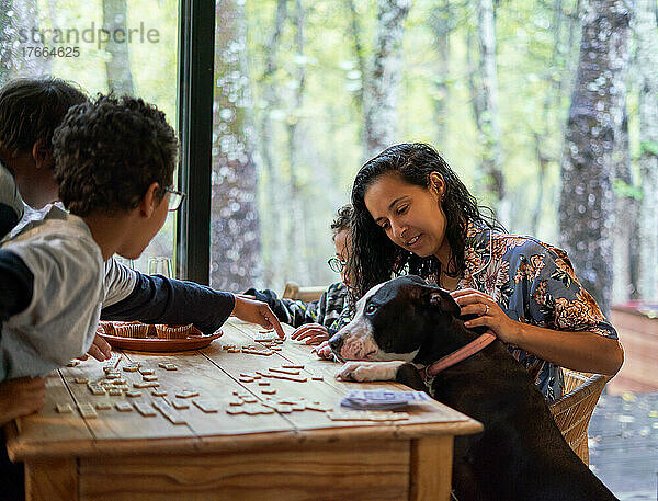 Familie mit Hund spielt Scrabble am Esstisch
