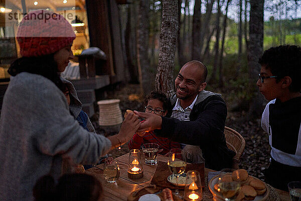 Familie isst bei Kerzenlicht am Tisch vor der Hütte