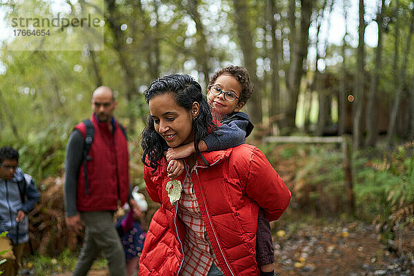 Mutter nimmt ihren Sohn bei einer Wanderung im Wald Huckepack