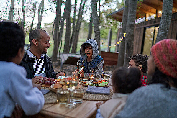 Familie isst am Tisch vor einer Hütte im Wald