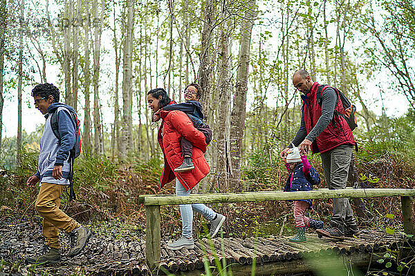Familie beim Überqueren eines Stegs auf einer Wanderung im Wald