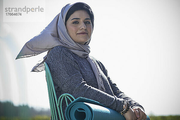Porträt selbstbewusste junge Muslimin im Hidschab mit Yogamatte