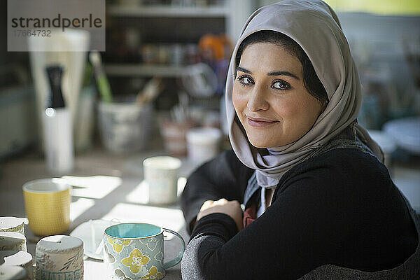Porträt selbstbewusste junge Künstlerin im Hidschab im Kunstatelier