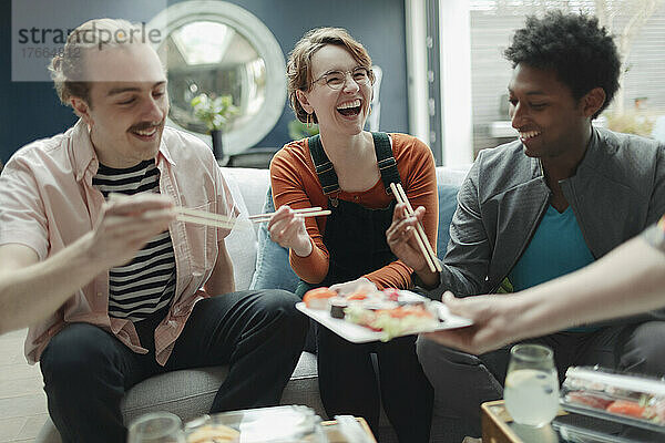 Glückliche Freunde teilen sich Sushi im Wohnzimmer