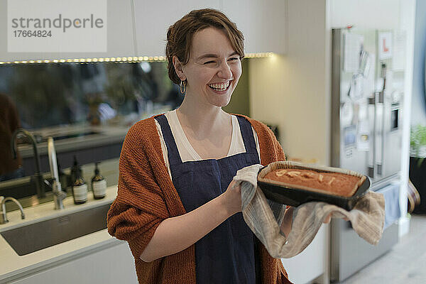 Glückliche junge Frau  die in der Küche einen Laib Kuchen backt