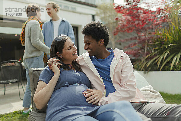 Glückliches  liebevolles  schwangeres Paar auf sonniger Veranda