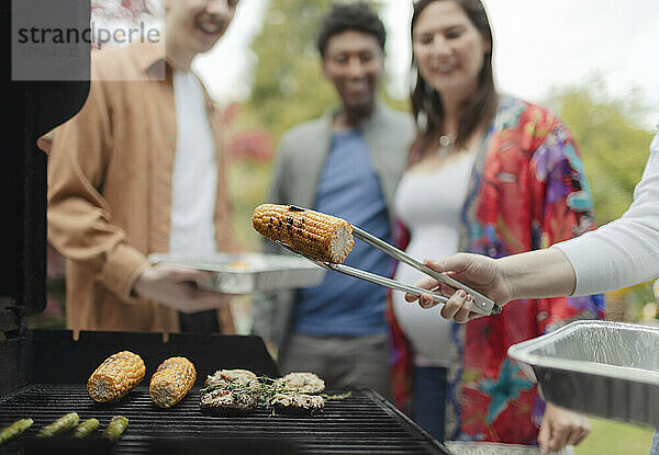 Freunde beim Grillen von Mais am Grill