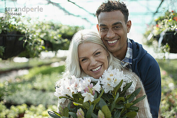 Portrait glückliches Paar mit Blumen im Gartengeschäft