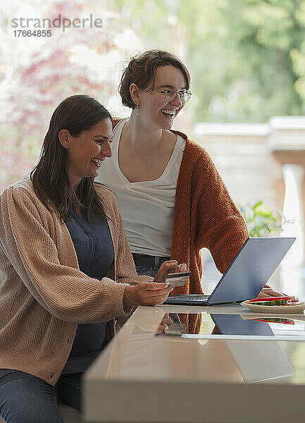 Glückliche Frauen Freunde Online-Shopping am Laptop in der Küche