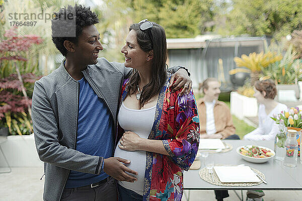 Glückliches schwangeres Paar beim Umarmen auf der Terrasse
