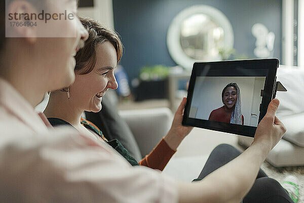 Glückliches junges Paar im Videochat mit einem Freund auf einem digitalen Tablet-Bildschirm