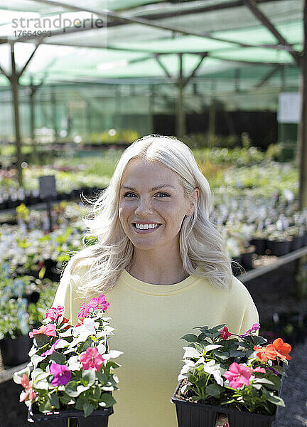 Porträt einer glücklichen Frau beim Einkaufen von Topfblumen in einem Gartengeschäft