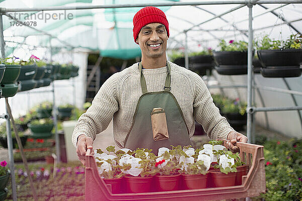 Porträt lächelnder männlicher Mitarbeiter einer Gärtnerei mit Topfblumen