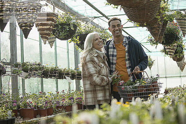 Glückliches Paar beim Einkaufen von Blumenampeln im Gewächshaus