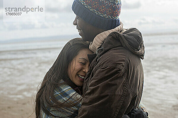 Glückliches  zärtliches Paar  das sich am Winterstrand umarmt