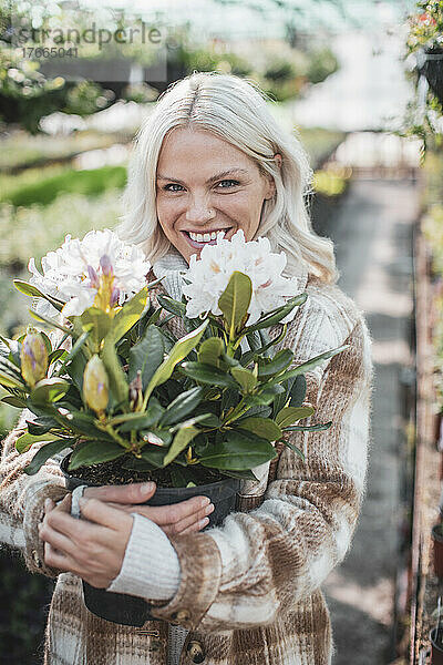 Porträt einer glücklichen Frau  die eine Topfblume hält