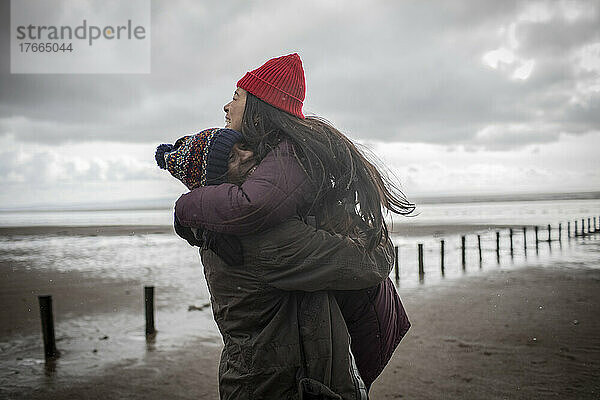 Glückliches  zärtliches Paar  das sich am nassen Winterstrand umarmt