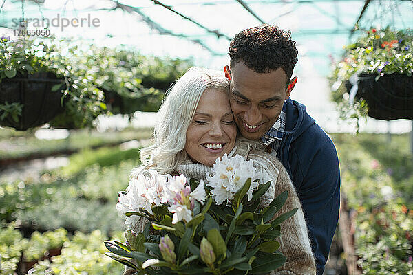 Glückliches  zärtliches Paar  das in einem Gartengeschäft Blumen kauft