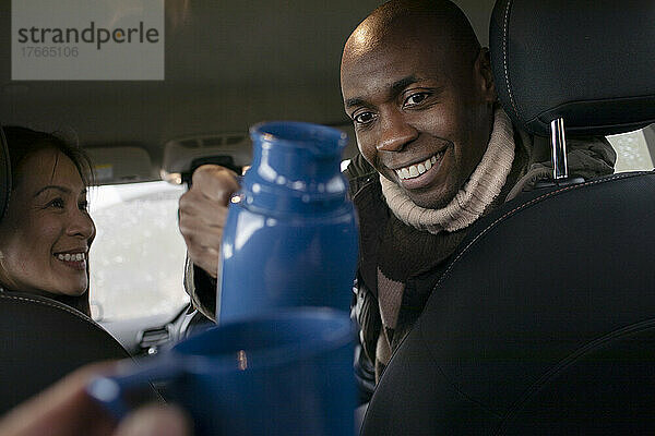 POV Mann gießt Kaffee aus Thermoskanne im Auto