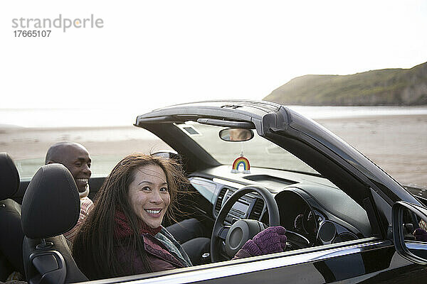 Portrait glückliches Paar im Cabrio am Winterstrand