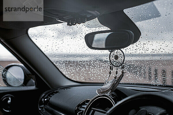 Traumfänger hängt am Rückspiegel im Auto am nassen Strand