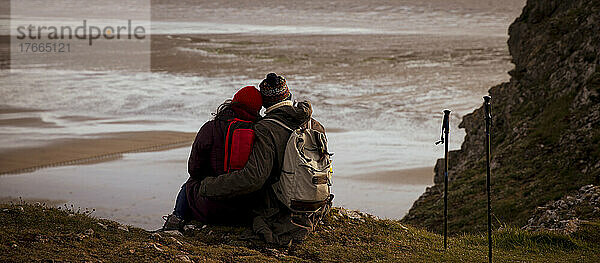 Verliebtes Wandererpaar auf Klippe über Winterstrand