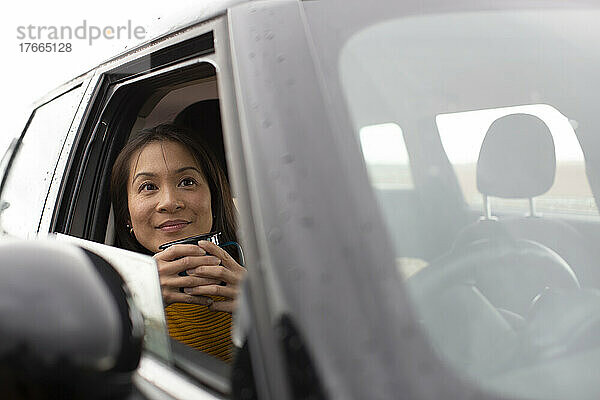 Glückliche Frau trinkt Kaffee im Auto