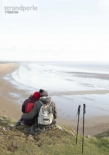Zärtliche Wanderer Paar umarmt auf Klippe mit Blick auf den Ozean Strand