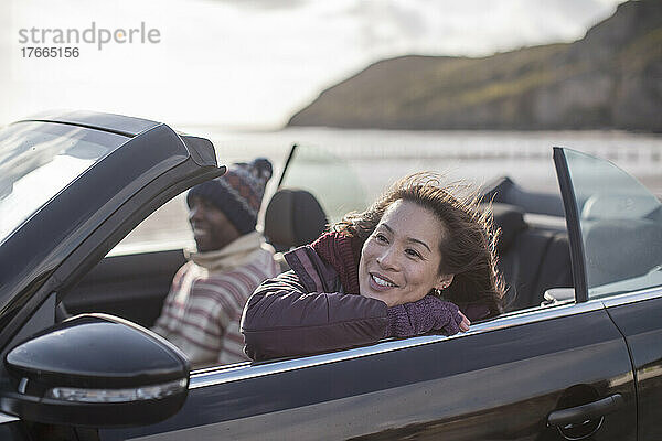 Glückliche Frau im Cabrio am Strand