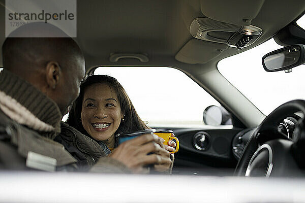 Glückliches Paar trinkt Kaffee im Auto