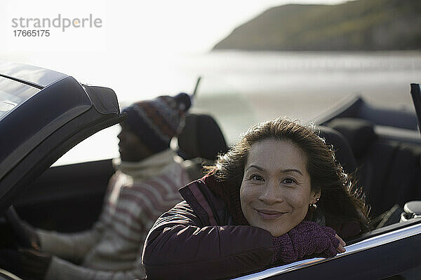 Portrait glückliche Frau im Cabrio am Strand