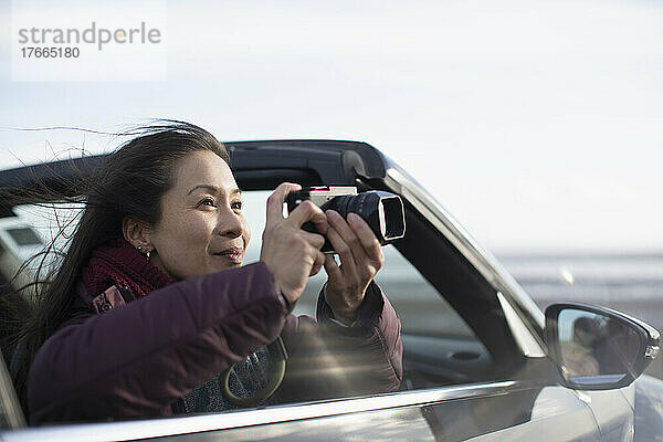Frau mit Digitalkamera im Cabrio