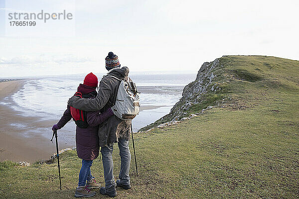 Verliebtes Wandererpaar auf einer Klippe oberhalb des Meeresstrandes