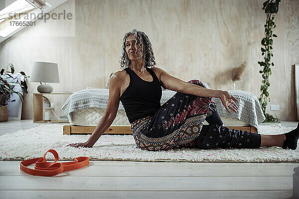Ältere Frau übt Yoga-Twist auf dem Schlafzimmerboden